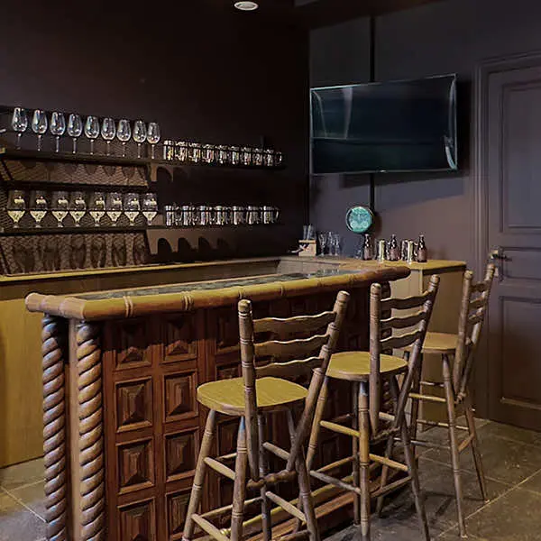 Houten toog met barkrukken en glazenrek in het bruin café