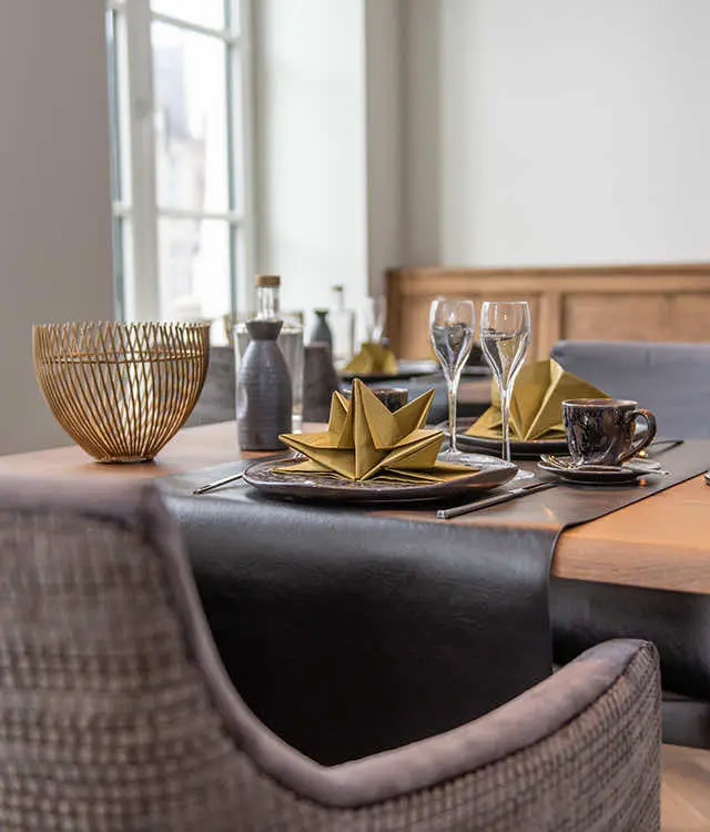 Gedekte ontbijttafel met gevouwen servetten en glazen bij het raam