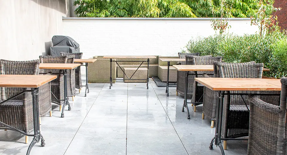 Het terras van Quay17 met houten tafels en rieten stoelen tussen het groen