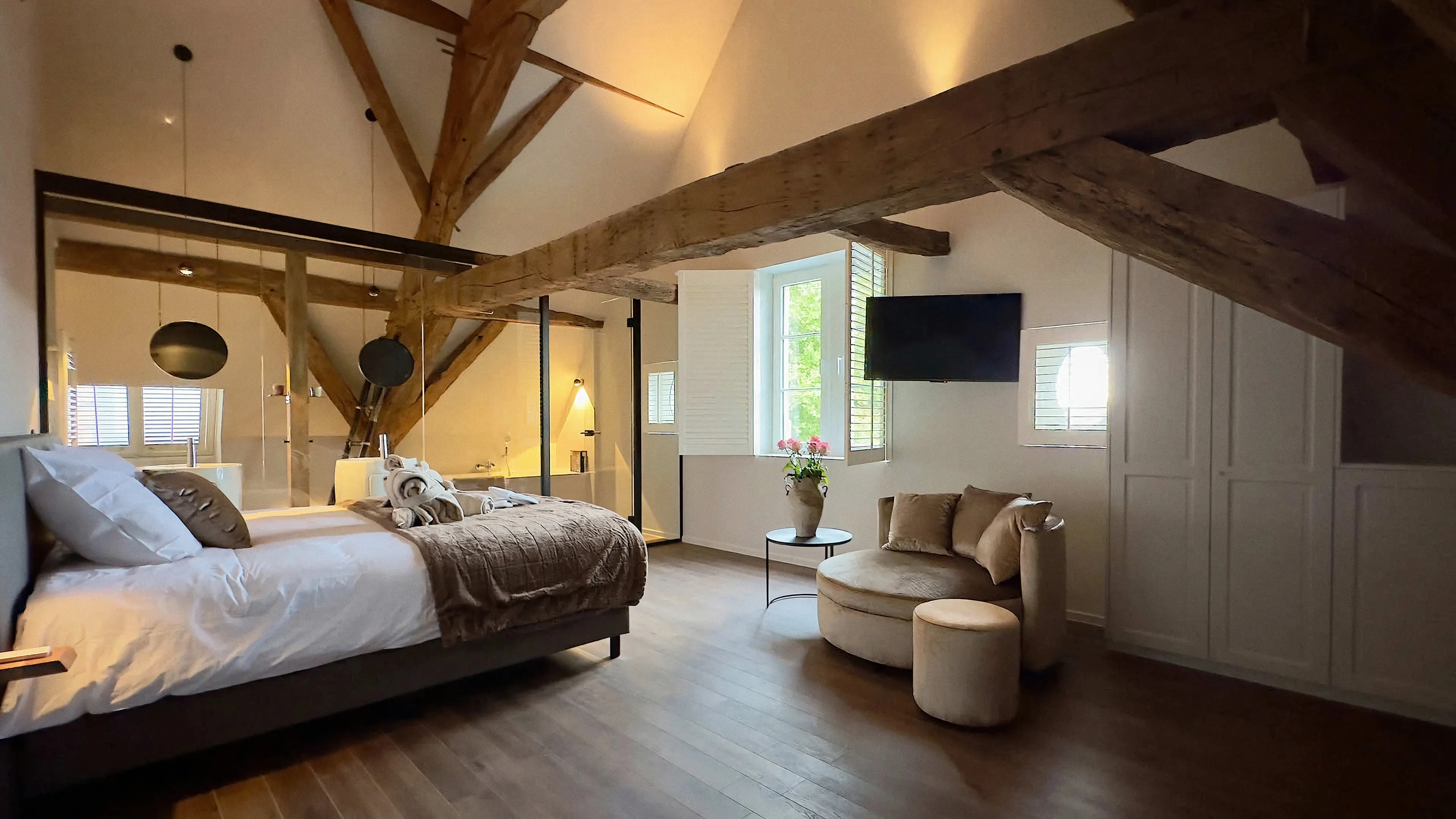 Ruime suite onder de eiken dakspanten met tweepersoonsbed, zithoek en glazen badkamerwand